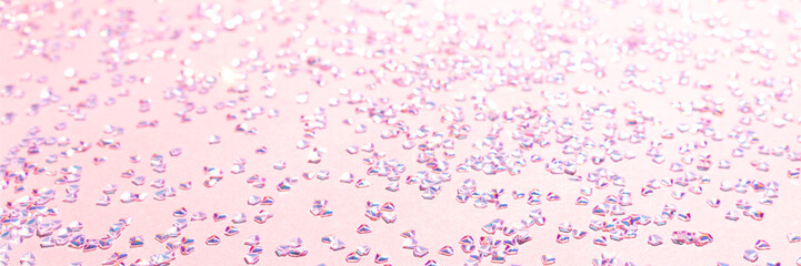Banner with silver crystal confetti on a pink background. Selective focus.