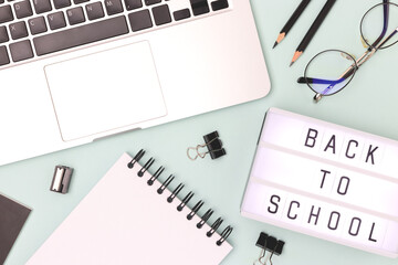 Back to school. Lightbox, eyeglasses, laptop and stationery on a blue background. Workspace for e-learning.