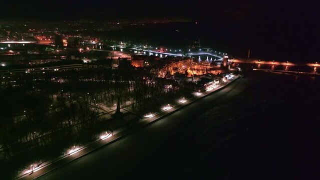 A mesmerizing drone film captures Kołobrzeg's lighthouse at night in winter, illuminating the coastal landscape with a serene and enchanting glow.