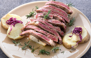 Fresh beef steack cut and cooked rare with potatoes, radicchio and rosemary close-up horizontally...