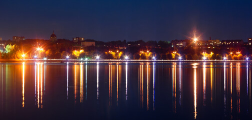 Panorama of the night city with the rays of lanterns and a beautiful reflection in the water....