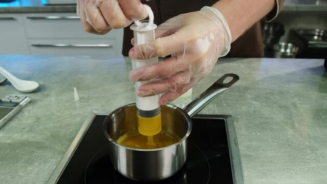 Hands on chef filling pastry tube with liquid mixture closeup. Man professionally acts wearing gloves which allows hygienic cooking