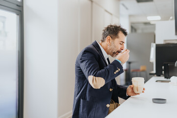 Fototapeta premium Handsome businessman taking his protein shake early in the morning at the office kitchen.