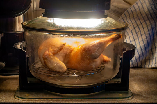 A chicken cooking in a halogen oven on a kitchen worktop