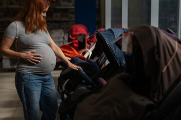Red-haired pregnant woman chooses a stroller in a children's store. 