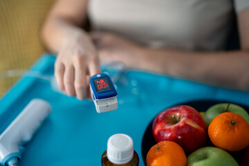 Woman's hand with pulse oximeter showing excellent oxygen saturation in blood and heartbeat rate...