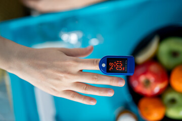 Pulse oximeter attached on finger showing oxygen saturation in blood and heartbeat rate after recovering from illness caused by Covid-19 pandemic.