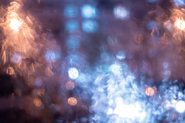 Bokeh light of a night city in the rain falls through the car window, blurred background.