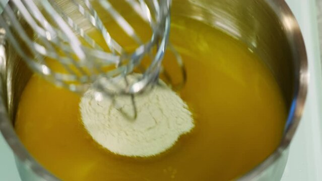 Cook mixes gelatin with orange juice using whisk and saucepan. Adding gelatin to juice makes excellent jelly for dessert