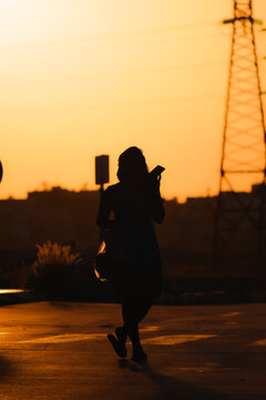A woman crossing the street in sunset