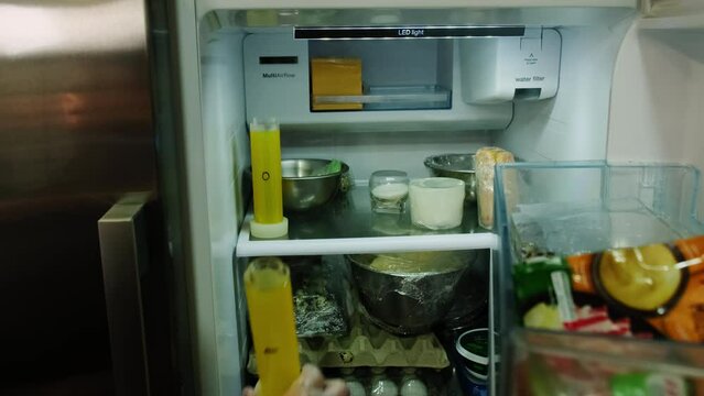 Kitchen worker places molds with liquid jelly mixture into fridge for solidifying. After couple of hours liquid will take cylindrical shape