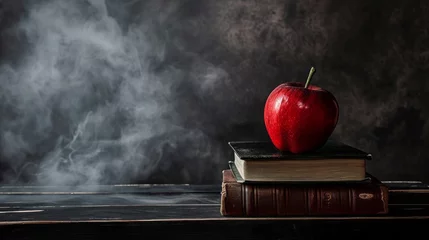 Fotobehang A red apple sitting on top of a stack of books on top of a black table next to a gray wall with smoke coming out of the back of it © vannet