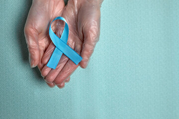 Blue cancer awareness ribbon with trail on blue background. concept of health and medicine