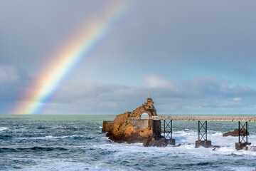 Vue distante du Rocher de la Vierge à Biarritz, France, après la pluie, avec un bel arc-en-ciel...