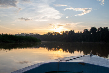 A serene dawn from the bow of a boat on a calm river