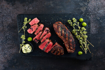 Barbecue dry aged angus roast beef steak with herb butter and dried oregano served as top view on a...