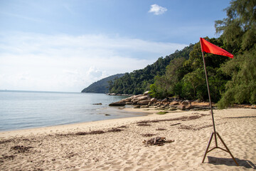 A serene beach scene with a red flag indicating caution.