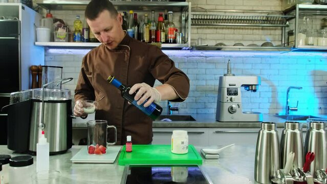 Chef sprinkles sugar powder in jug with strawberries. Culinarian also adds wine to get perfect taste of molecular cuisine recipe