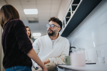 Positive atmosphere in a modern kitchen with coworkers having a conversation over morning coffee.