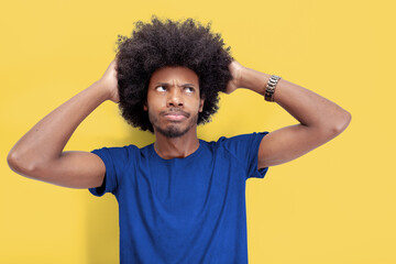 Lost in Thought: Brazilian man with hands on head against a yellow background