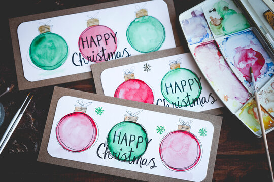 Overhead view of Homemade Christmas Cards on a table with watercolour paints