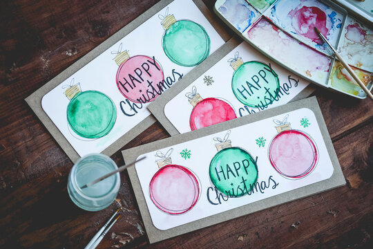 Overhead view of Homemade Christmas Cards on a table with watercolour paints