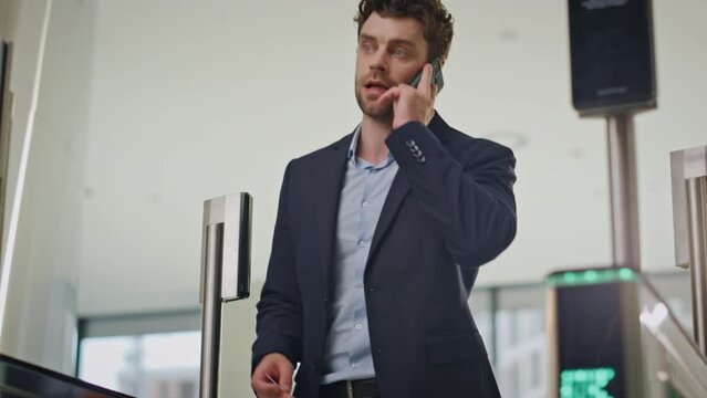 Office manager walking checkpoint security talking cellphone. Employee entering 