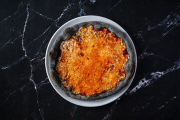 top view plate with charcoal margherita pizza on black marble background