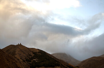 Gergeti Trinity Church on mountain peak with cloudy sky on background in Stepantsminda (Kazbegi), Georgia