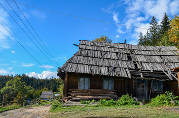 Fototapeta na wymiar Rustic landscape with old wooden house abandoned in the village in the mountains. Carpathians, Ukraine