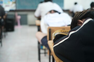A female student who is tired from taking a difficult exam is discouraged and falls asleep during...
