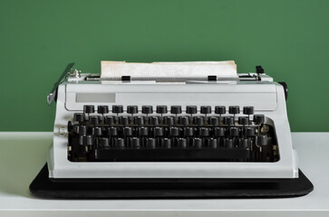 Vintage typewriter on table near green wall