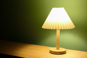 Glowing lamp on wooden table in dark room