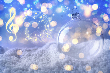 Music notes and Christmas ball on snow, bokeh effect