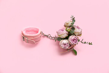Composition with handcuffs from sex shop and beautiful flowers on pink background - obrazy, fototapety, plakaty