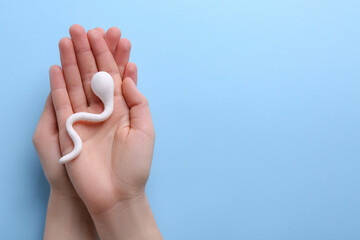 Reproductive medicine. Woman holding figure of sperm cell on light blue background, top view with...
