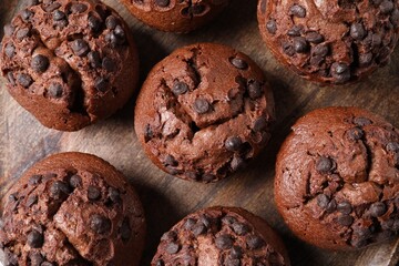 Tasty chocolate muffins on wooden board, flat lay