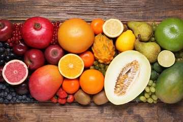 Many different fresh fruits and berries on wooden table, flat lay