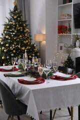Christmas table setting with festive decor and dishware in room