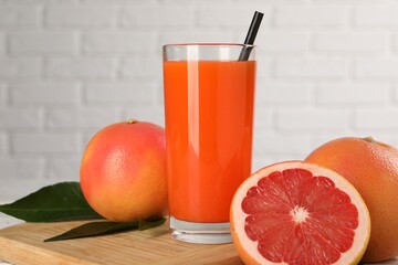 Tasty grapefruit juice in glass and fresh fruits on table, closeup
