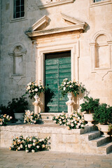 Fototapeta na wymiar Wedding semi-arch with bouquets of flowers stands on the steps of St. Mark Church. Perast, Montenegro