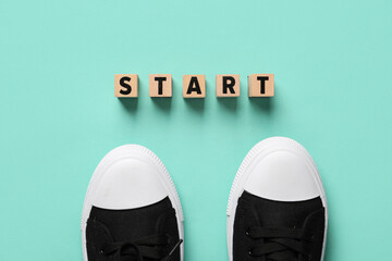 Cubes with word START and sneakers on green background