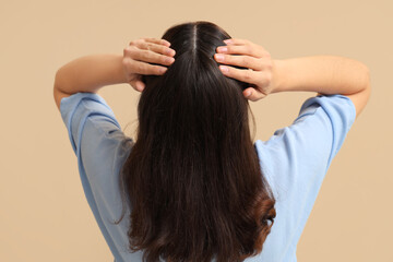 Naklejka premium Young woman with dandruff on beige background, back view