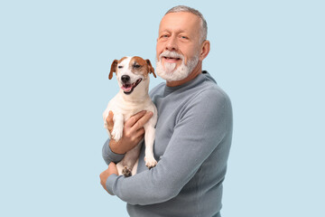 Senior man with cute dog on light blue background