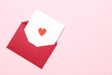 Composition with envelope, card and paper heart on pink background. Valentine's Day celebration