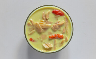 A typical Indonesian food is young bamboo vegetables or "lodeh rebung" with the addition of red chillies, cooked in coconut milk and yellow in color on bowl. closeup, top view