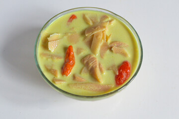 A typical Indonesian food is young bamboo vegetables or "lodeh rebung" with the addition of red chillies, cooked in coconut milk and yellow in color on bowl. closeup, top view
