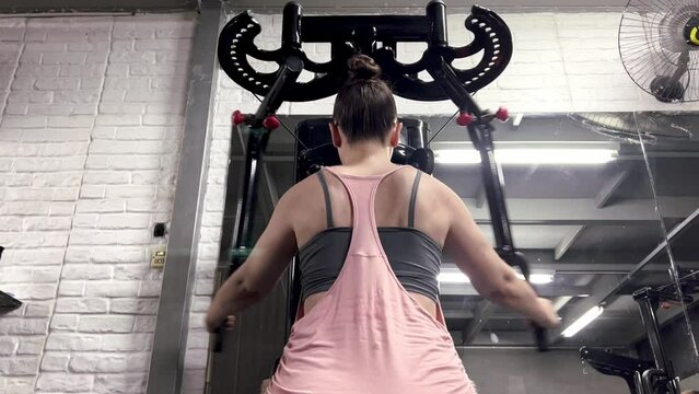 Close-up shot of Caucasian female athlete pulling up crossbar. A strong determined woman exercising in the gym, High quality 4k footage