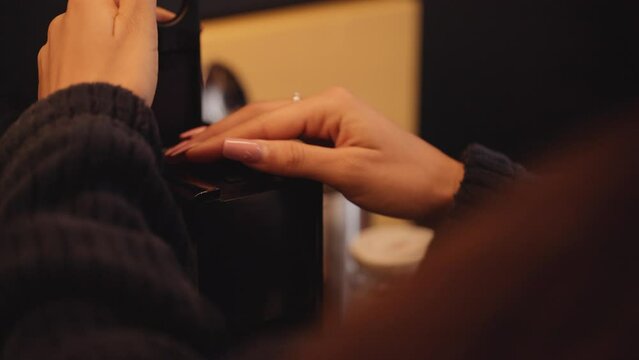 Female hand places espresso pod into Nespresso coffee machine, shallow focus