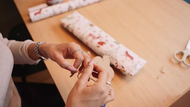 Woman prepares string to use for decoration a Christmas gift, close-up